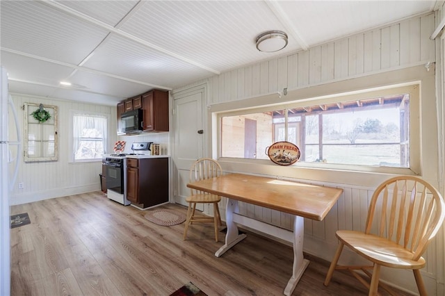 kitchen with light wood finished floors, light countertops, black microwave, and gas range oven