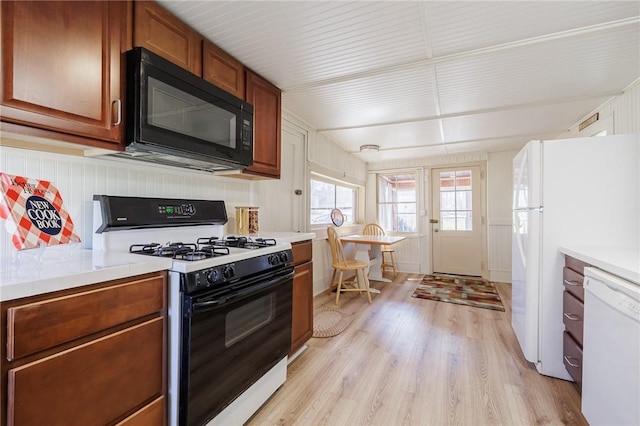 kitchen with white appliances, brown cabinetry, light wood-type flooring, and light countertops