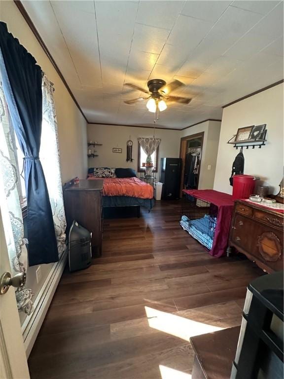 bedroom featuring a walk in closet, crown molding, wood finished floors, a closet, and a ceiling fan