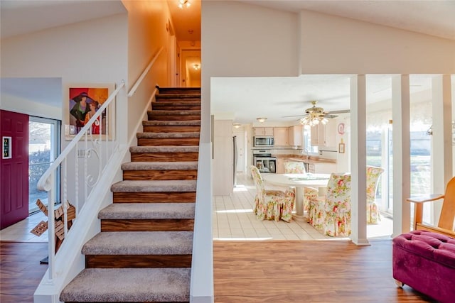 stairs featuring a ceiling fan, lofted ceiling, and wood finished floors