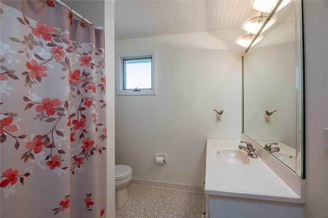 bathroom with toilet, a textured ceiling, tile patterned flooring, baseboards, and vanity