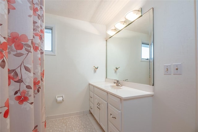 full bath featuring tile patterned floors, a textured ceiling, a wealth of natural light, and vanity