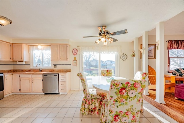 kitchen with light brown cabinets, light tile patterned floors, dishwasher, and a sink