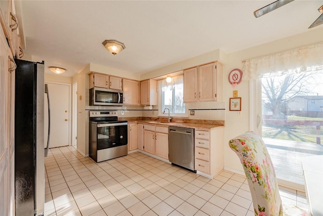 kitchen featuring light brown cabinetry, light countertops, appliances with stainless steel finishes, and a sink