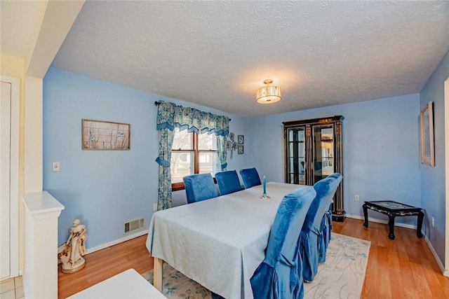 bedroom featuring light wood-style flooring, baseboards, visible vents, and a textured ceiling