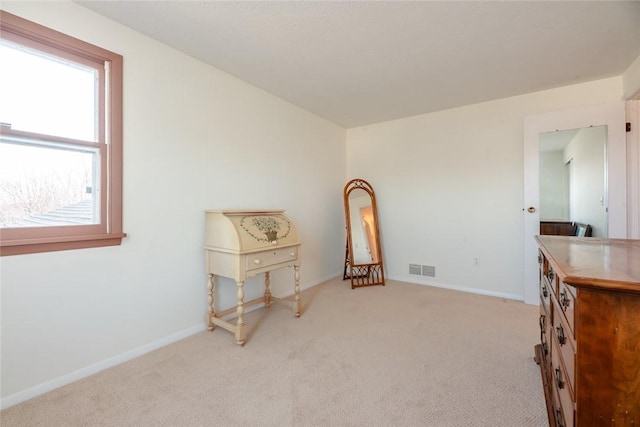 interior space featuring visible vents, light colored carpet, and baseboards