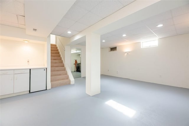 basement with stairway, recessed lighting, and a drop ceiling