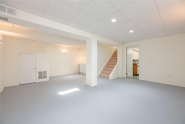 finished basement with visible vents, recessed lighting, stairs, and a paneled ceiling