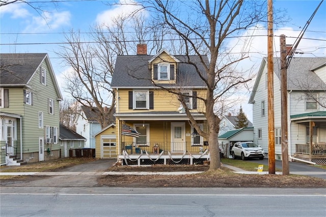 traditional style home with driveway, covered porch, an outdoor structure, a garage, and a chimney