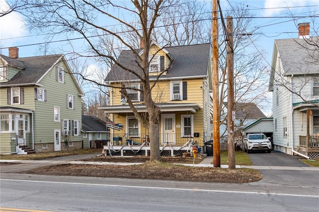 traditional style home with an outbuilding, driveway, entry steps, a residential view, and covered porch