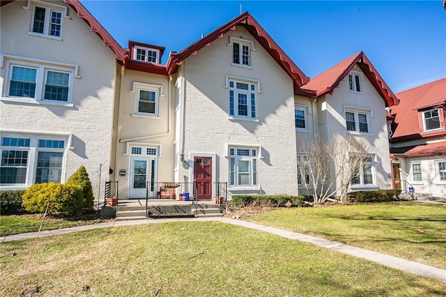 view of front facade with brick siding and a front lawn