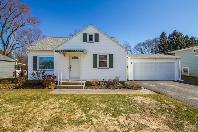 bungalow-style house with a front lawn, an attached garage, driveway, and a shingled roof