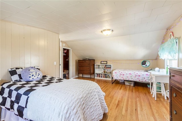 bedroom with wooden walls, light wood-style flooring, and vaulted ceiling