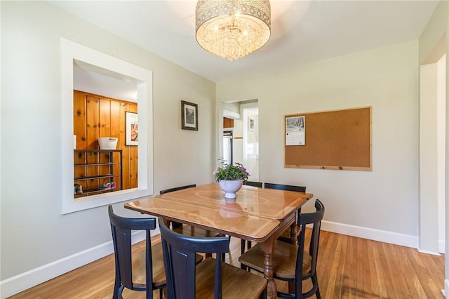 dining room with a notable chandelier, wood finished floors, and baseboards