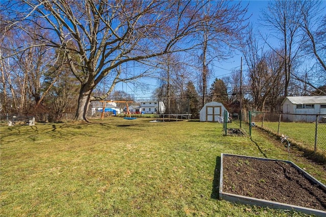 view of yard with fence, a garden, an outdoor structure, a storage unit, and a trampoline