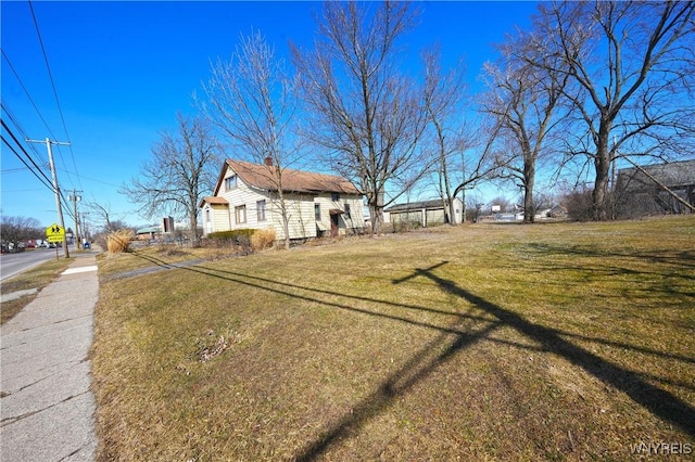 view of side of property with a chimney and a yard