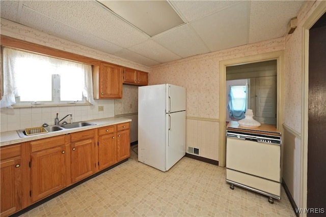 kitchen featuring a wainscoted wall, visible vents, white appliances, wallpapered walls, and light floors