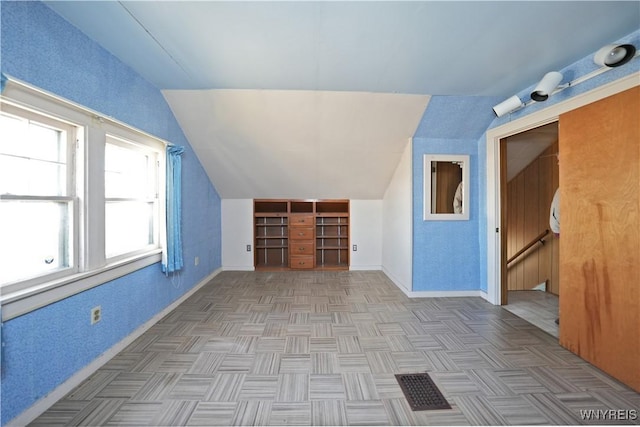 additional living space with baseboards and vaulted ceiling