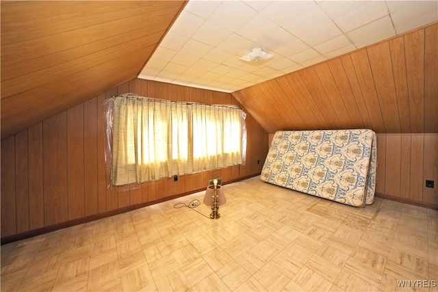 bonus room with baseboards, lofted ceiling, and wooden walls