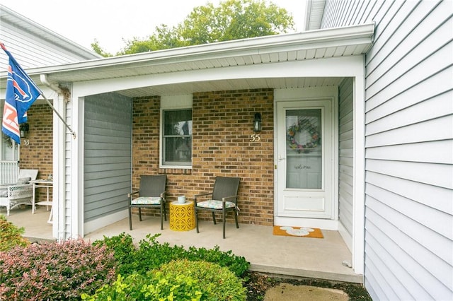 view of exterior entry with a porch and brick siding