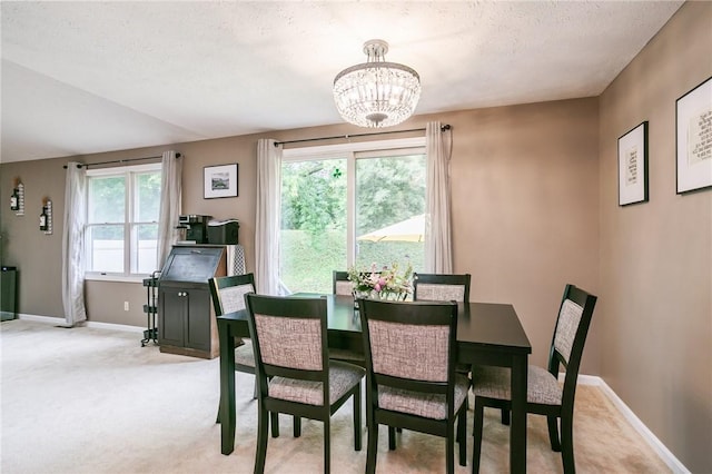 dining area featuring a notable chandelier, plenty of natural light, light colored carpet, and baseboards