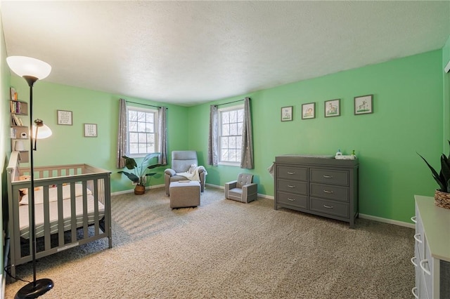 carpeted bedroom featuring baseboards, a textured ceiling, and a crib