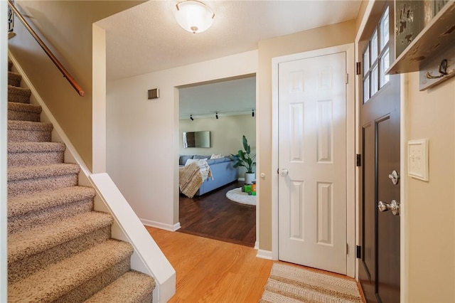 foyer entrance featuring baseboards, stairs, and light wood-style floors