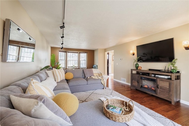 living room featuring visible vents, baseboards, wood finished floors, and rail lighting