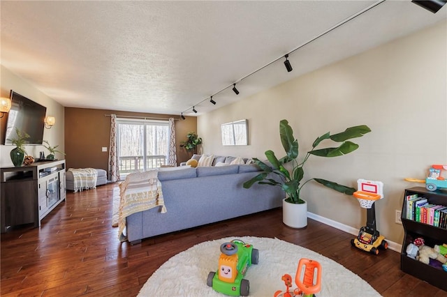 living area featuring hardwood / wood-style floors, rail lighting, baseboards, and a textured ceiling