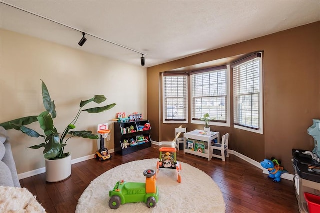 playroom featuring hardwood / wood-style floors, track lighting, and baseboards