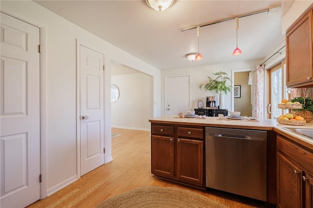 kitchen featuring baseboards, a peninsula, light countertops, light wood-style floors, and dishwasher