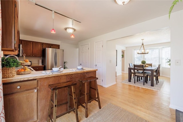 kitchen featuring decorative light fixtures, light wood-type flooring, light countertops, appliances with stainless steel finishes, and a peninsula