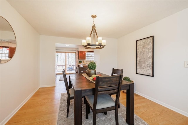 dining room featuring light wood-style flooring, baseboards, and a chandelier