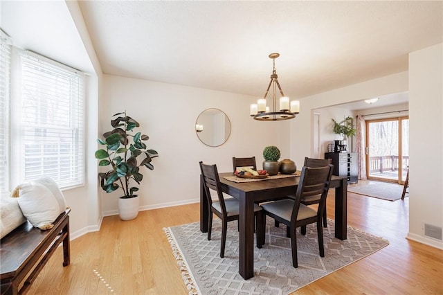 dining space featuring a chandelier, visible vents, light wood-type flooring, and baseboards