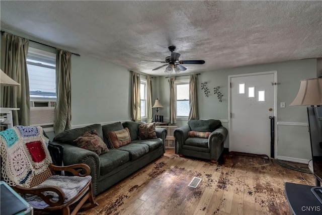 living area with cooling unit, a textured ceiling, a ceiling fan, and hardwood / wood-style flooring