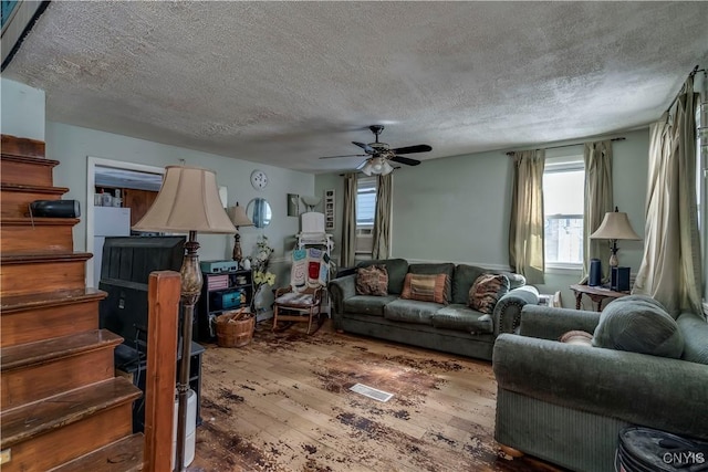 living area with a ceiling fan, wood finished floors, and a textured ceiling