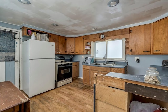 kitchen with a sink, freestanding refrigerator, brown cabinetry, gas stove, and open shelves