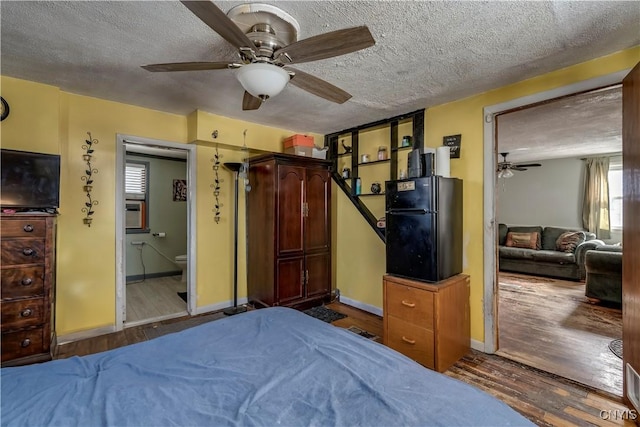 bedroom with baseboards, freestanding refrigerator, a textured ceiling, a ceiling fan, and dark wood-style flooring