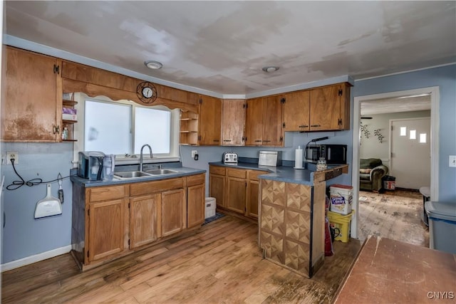 kitchen featuring open shelves, wood finished floors, brown cabinetry, and a sink