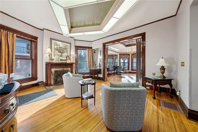 living room with baseboards, light wood finished floors, a high end fireplace, and crown molding