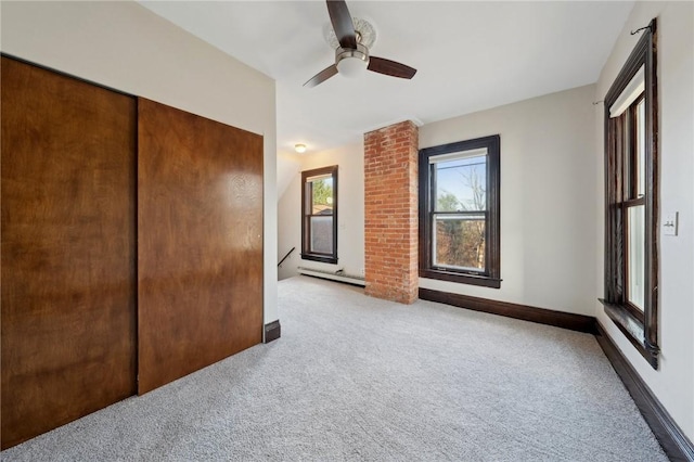 unfurnished bedroom with a closet, carpet, a baseboard radiator, baseboards, and ceiling fan