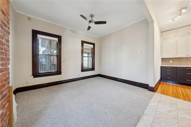 unfurnished room with track lighting, ceiling fan, and baseboards