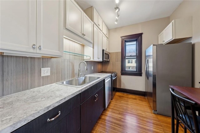 kitchen with light wood-style flooring, a sink, light countertops, appliances with stainless steel finishes, and white cabinetry