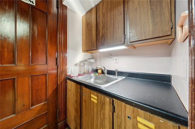 kitchen featuring dark countertops, brown cabinets, and a sink