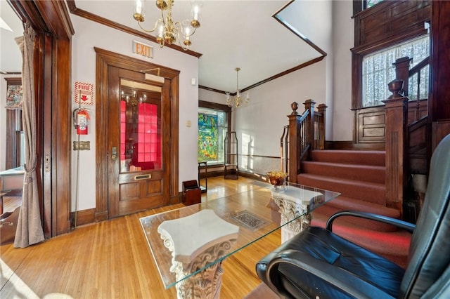 foyer featuring wood finished floors, a chandelier, stairs, and ornamental molding