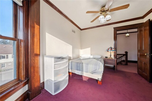 carpeted bedroom featuring a ceiling fan, crown molding, baseboards, and visible vents