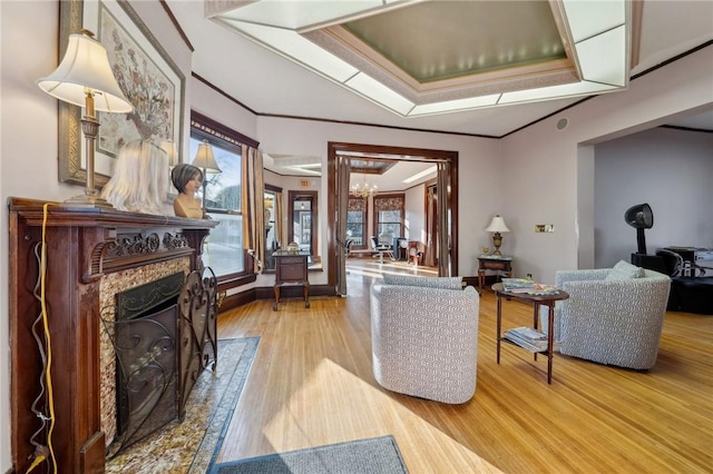 living area with baseboards, a fireplace, wood finished floors, and crown molding