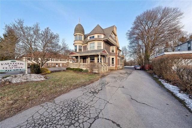 view of front facade featuring covered porch, driveway, and a front lawn