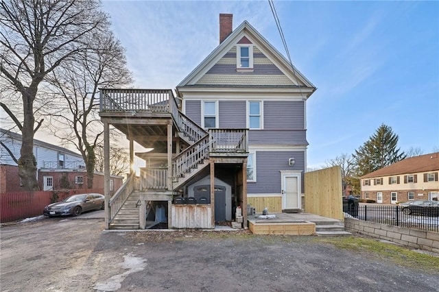 view of front facade featuring a chimney, a deck, stairs, and fence