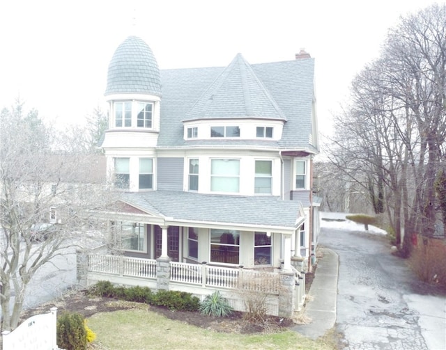 victorian-style house with a porch, driveway, and a chimney